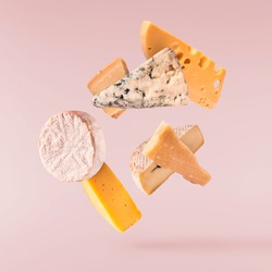 Various types of fresh tasty cheese fall in the air isolated on pink background . Food levitation concept, high quality image