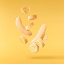 Fresh ripe baby bananas falling in the air isolated on yellow background. Food levitation concept. High resolution image