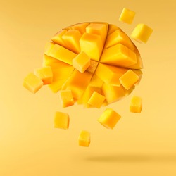 Fresh ripe mango falling in the air isolated on yellow background. Food levitation concept. High resolution image