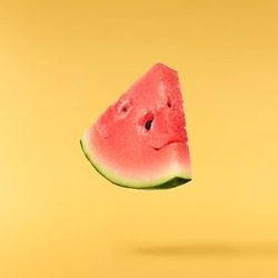 Fresh raw watermelon falling in the air isolated on yellow backgeound. Food levitation or zero gravity conception. igh resolution image.