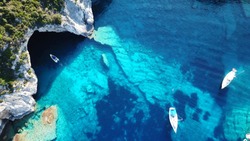 Aerial drone photo of sail boats anchored in tropical Caribbean island paradise bay with white rock caves and turquoise clear sea