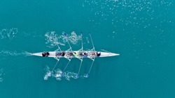 Aerial drone top down photo of sport canoe operated by team of young women in emerald calm sea waters
