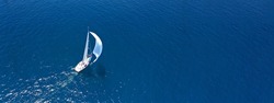 Aerial drone ultra wide panoramic photo of beautiful sail boat with white sails cruising deep blue sea near Mediterranean destination port