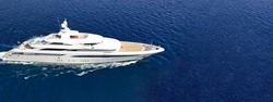 Aerial drone ultra wide panoramic photo of beautiful modern super yacht with wooden deck cruising in high speed deep blue open ocean sea