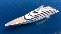 Aerial drone photo of luxury mega yacht with wooden deck and helipad anchored in deep blue Aegean sea