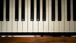 Top view of  a piano keyboard with wooden floor background in vintage looks.