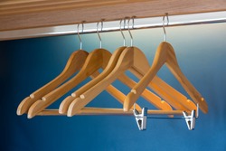 Close up of wooden hangers inside a blue closet with selective focus on the stainless pin.