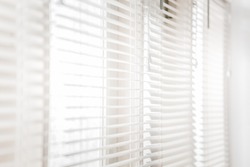 White shutters on windows with bright sunlight shining through.
