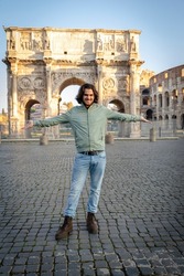 Happy moment in Rome. Young smiling man posing for a photo spreading his arms in front of the Arch of Titus.