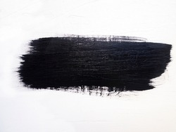 A trace of black paint from a paintbrush on a white wall.