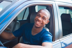 young black handsome cab driver smiling inside his blue car