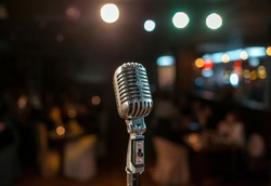vintage microphone on a stand standing on a lighted stage. view of the auditorium from the stage. Microphone on a lighted stage. Karaoke.