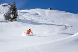 freeride skier skiing downhill through fresh powder snow