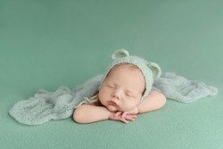 Sleeping newborn baby on a green background. Photoshoot for the newborn. A few days from birth.