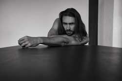 Handsome brutal man with beard and cool long hair.Sexy topless athletic body. Confident, attractive, stylish. Fashion shooting. Actor. Black and white