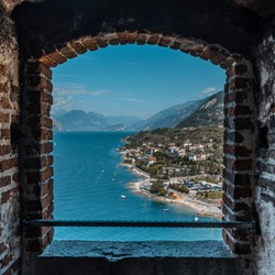 View of lake Garda through a stone window from a castle