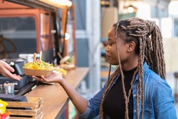 Afro american woman getting a fast food tray from a fast food truck