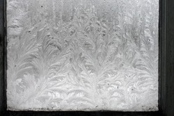 The abstract creation of window frost on window glass. Ornamental floral frost shapes on the window. Frost flowers. Poland, Europe