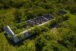 Ruins of an old abandoned building in a thicket of grass and shrubs. Drone view