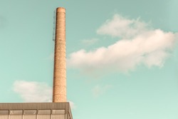 Brick Factory or Industrial Chimney with Steel Confining Rings against Teal Sky with Fluffy Clouds. Minimal Aesthetics. High Resolution Photography.