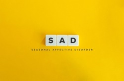 Seasonal affective disorder (SAD) banner. Winter Depression. Block Letter Tiles on Yellow Background. Minimal Aesthetics.