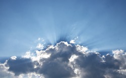 Dark clouds with sun rays over a blue sky