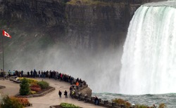 Canadian viewing area at Horseshoe Falls, Niagara Falls, Ontario, Canada with Canadian flag in the foreground. The differences between the US and Canada might be represented by the Niagara chasm