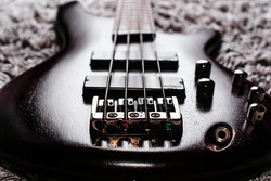 Rosewood bass electric guitar with four strings on the gray carpet closeup