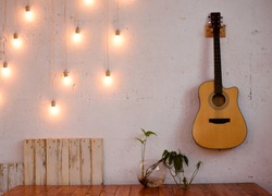 The textured white wall is decorated with yellow lights and a guitar.