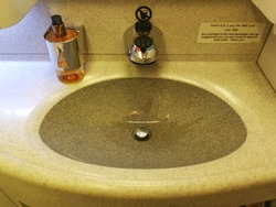 A sink and soap in lavatory on airplane, including the instruction label.