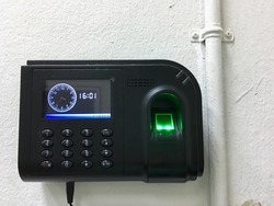 The fingerprint scanner with clock on the wall. Equipment for working time in office.