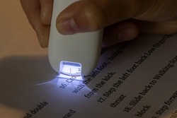 Kid's hand holding a reader and translator pen that scans English text and translates it in an instant.