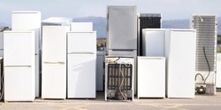 Old fridge freezer refrigerator refrigerant gas at refuse dump skip recycle stacked pile plant help environment reduce pollution white silver 