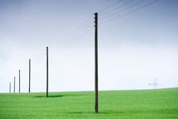 Telegraph poles and telephone communication cables through green field