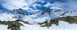 Panorama of snowy mountain peaks in winter. Winter mountain panorama in snow. Snowy mountain panoramic landscape. Winter snow mountains