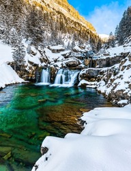 Mountain waterfall stream among the snow. Waterfall in snowy mountains in winter. Winter mountain waterfall in snow. Snowy mountains waterfall in winter