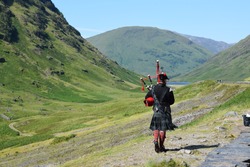 A Scotsman playing bagpipes in Scottish Highlands