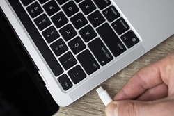 Connect the usb type-c cable to the computer. Connecting the usb type-c cable to the charging connector close-up. A man connects usb type-c cable to a laptop connector. High quality photo