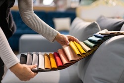 The woman chooses the fabric on the sofa. A young women looks at tissue samples. Selects the color of the sofa. Textile industry background. Tissue catalog