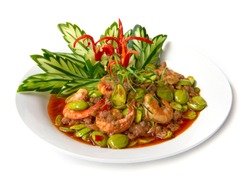 Shrimp paste stir fried curry with Bitter bean or stink bean and fresh shrimp. Thai food fusion style decorate with carved leaf cucumber and chili pepper side view isolated on white background