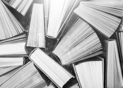 A black and white image of hardback books or text books from above. Books and reading are essential for self improvement, gaining knowledge and success in our careers, business and personal lives
