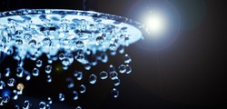 Shower head with water stream on black background