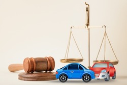 Little crashed autos on table in courtroom. Gavel and two small toy car models on desk. Concept of lawyer services, civil court trial, vehicle accident case study, and insurance coverage