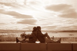 Sepia image of couple relaxing together by the lake shore of Lake Argentino in El Calafate, Patagonia, Argentina