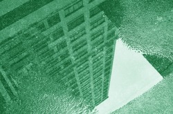 Surreal pop art of high buildings reflecting on the puddle in green color
