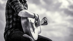 Man's hands playing acoustic guitar, close up. Acoustic guitars playing. Music concept. Black and white.