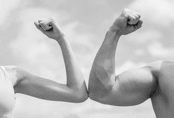 Sporty man and woman. Muscular arm vs weak hand. Vs, fight hard. Competition, strength comparison. Rivalry concept. Hand, man arm fist Close-up. Black and white.