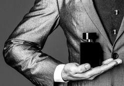Fragrance smell. Men perfumes. Fashion cologne bottle. Man in formal suit, bottle of perfume, closeup. Black and white.