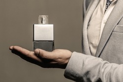 Masculine perfume. Male holding up bottle of perfume. Man perfume, fragrance. Perfume or cologne bottle and perfumery, cosmetics, scent cologne bottle, male holding cologne.