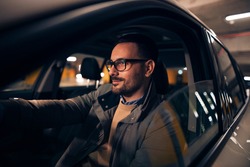 Side view portrait of a handsome stylish man driving car at night